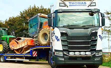 A Thomas Plant flatbed carrying a tractor
